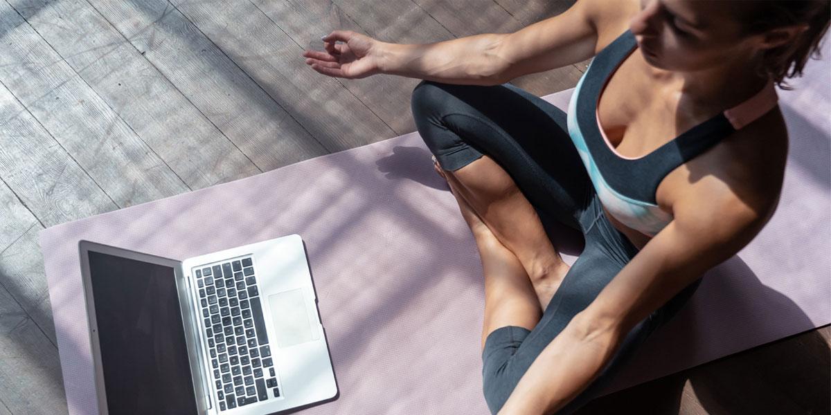 做瑜伽姿势的女人拿着笔记本电脑.
