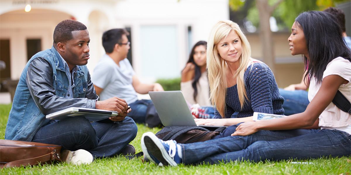 学生们坐在大学草坪上聊天.
